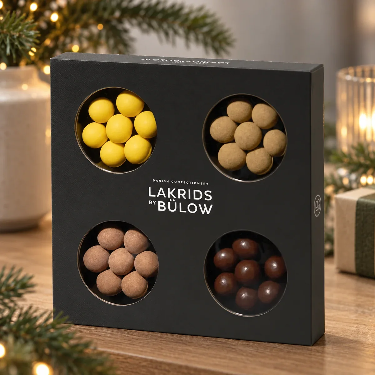 Small Selection Box Lakrids by Bülow, 175 g LAKRIDS BY BÜLOW Small Selection Box als winterliches Lakritz-Geschenkset auf einem festlich dekorierten Büro-Sideboard.