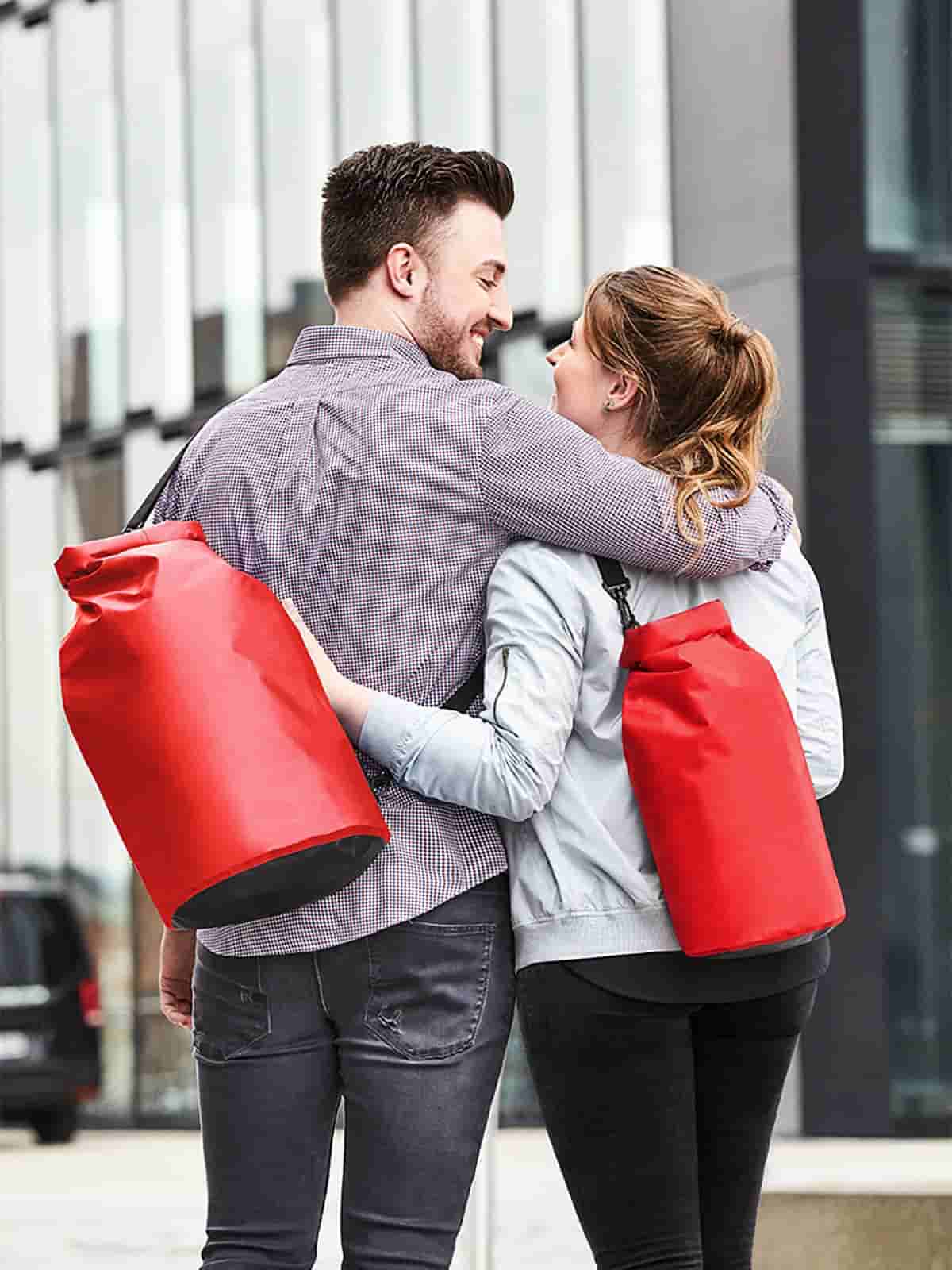 Frau und Mann mit Halfar Drybag SPLASH in Rot – auffällige wasserdichte Tasche für Outdoor, Freizeit und Reisen