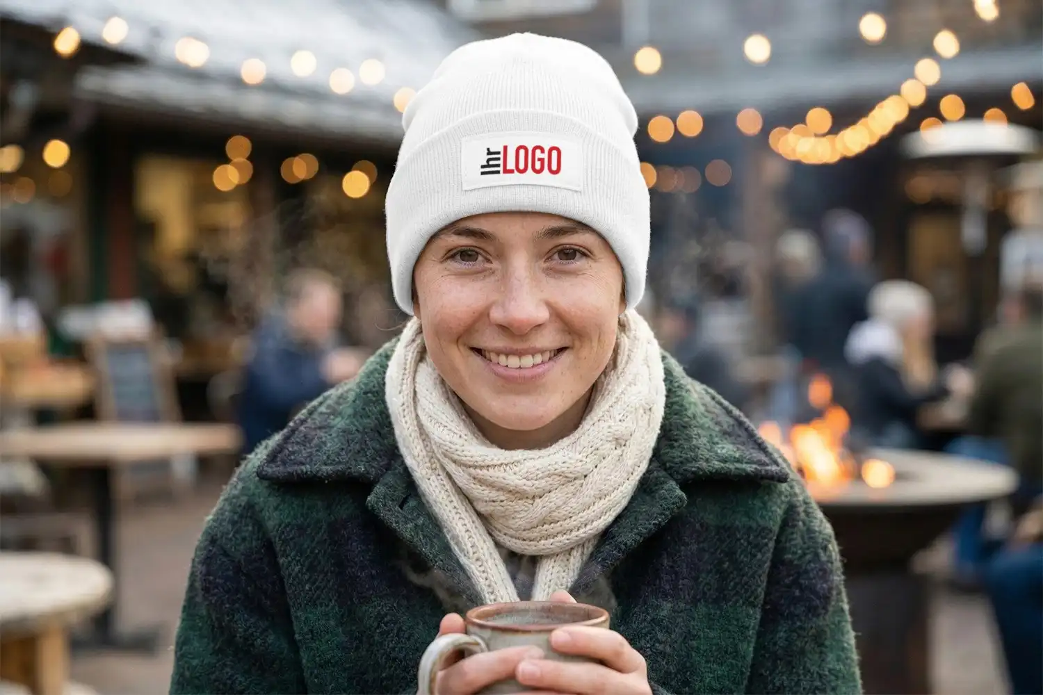Frau trägt Boreas Beanie in Weiß und hält heißen Drink – stylischer Werbeartikel für Winter, Alltag und Promotion