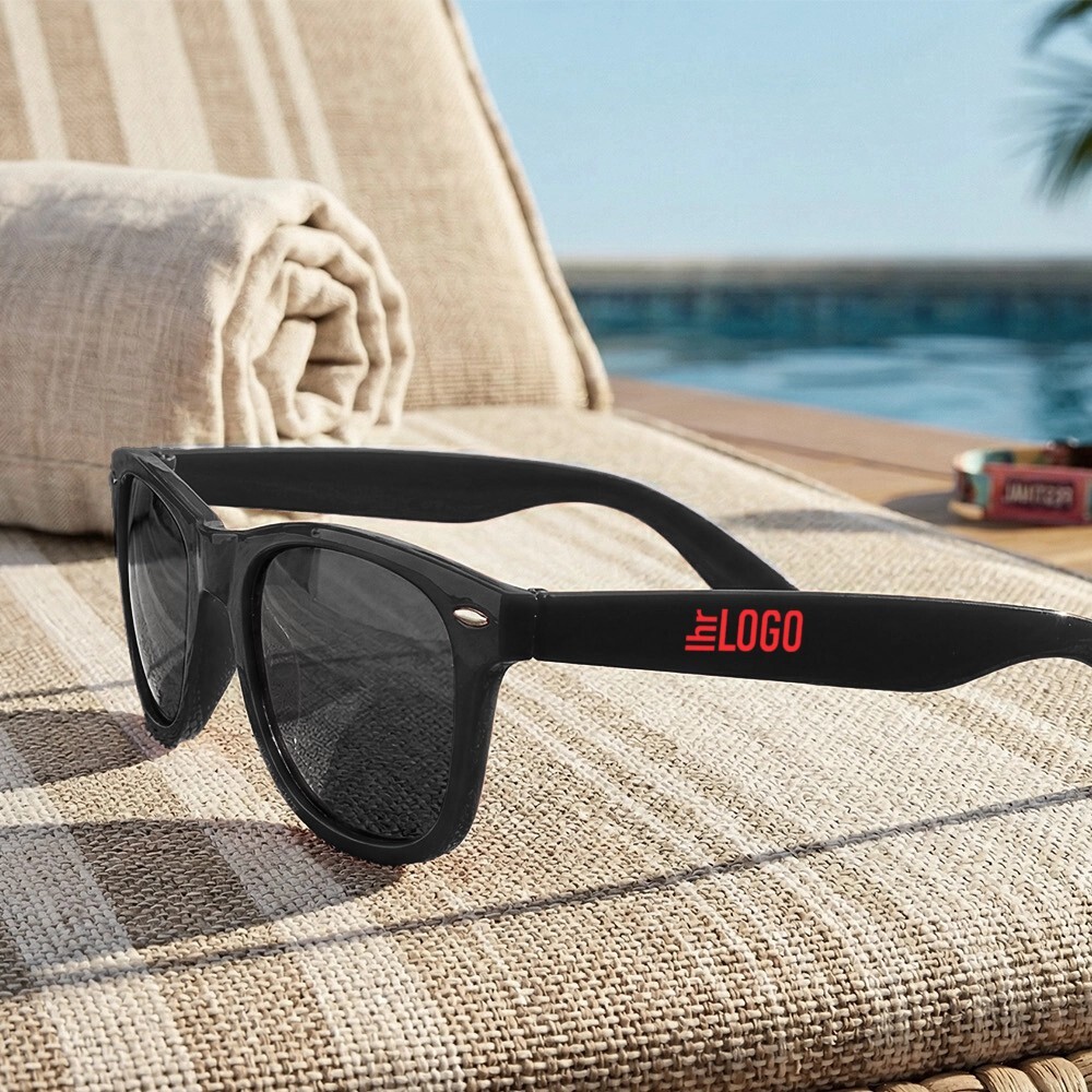 Sun Ray Sonnenbrille in Schwarz auf Liegestuhl am Strand – sommerlicher Werbeartikel für Urlaub, Events und Promotion
