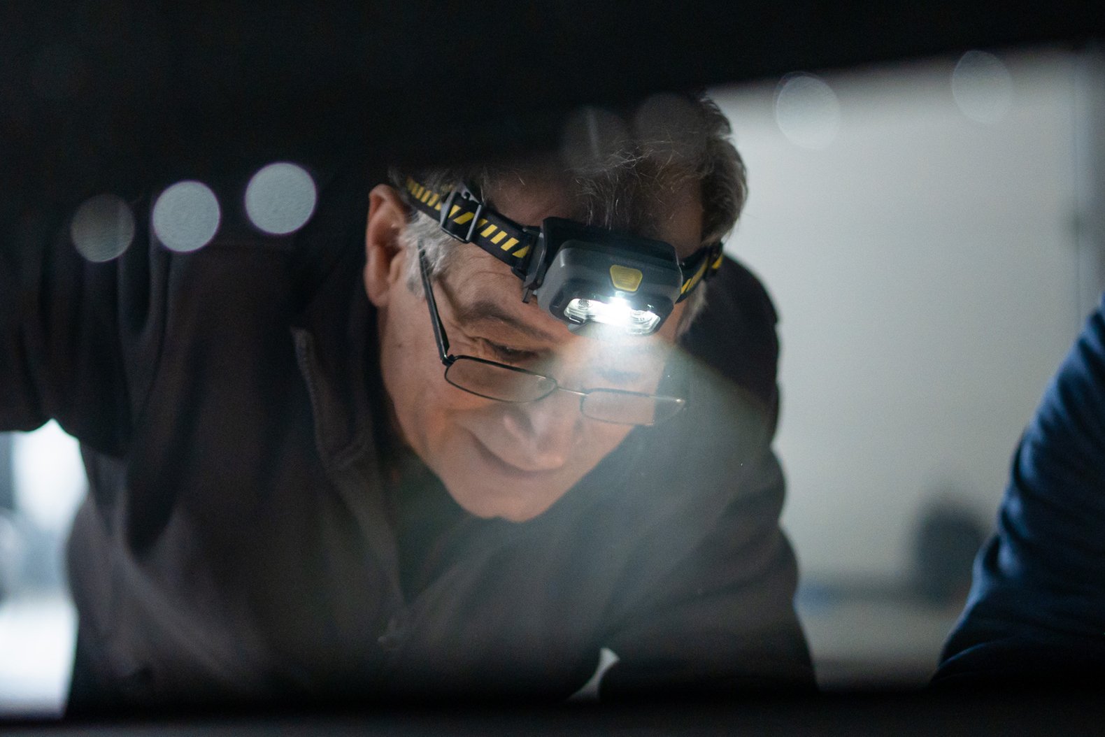 Mann mit LEDLENSER HF6R Core Stirnlampe bei der Arbeit im Dunkeln – Stirnlampe mit Logo für Kunden