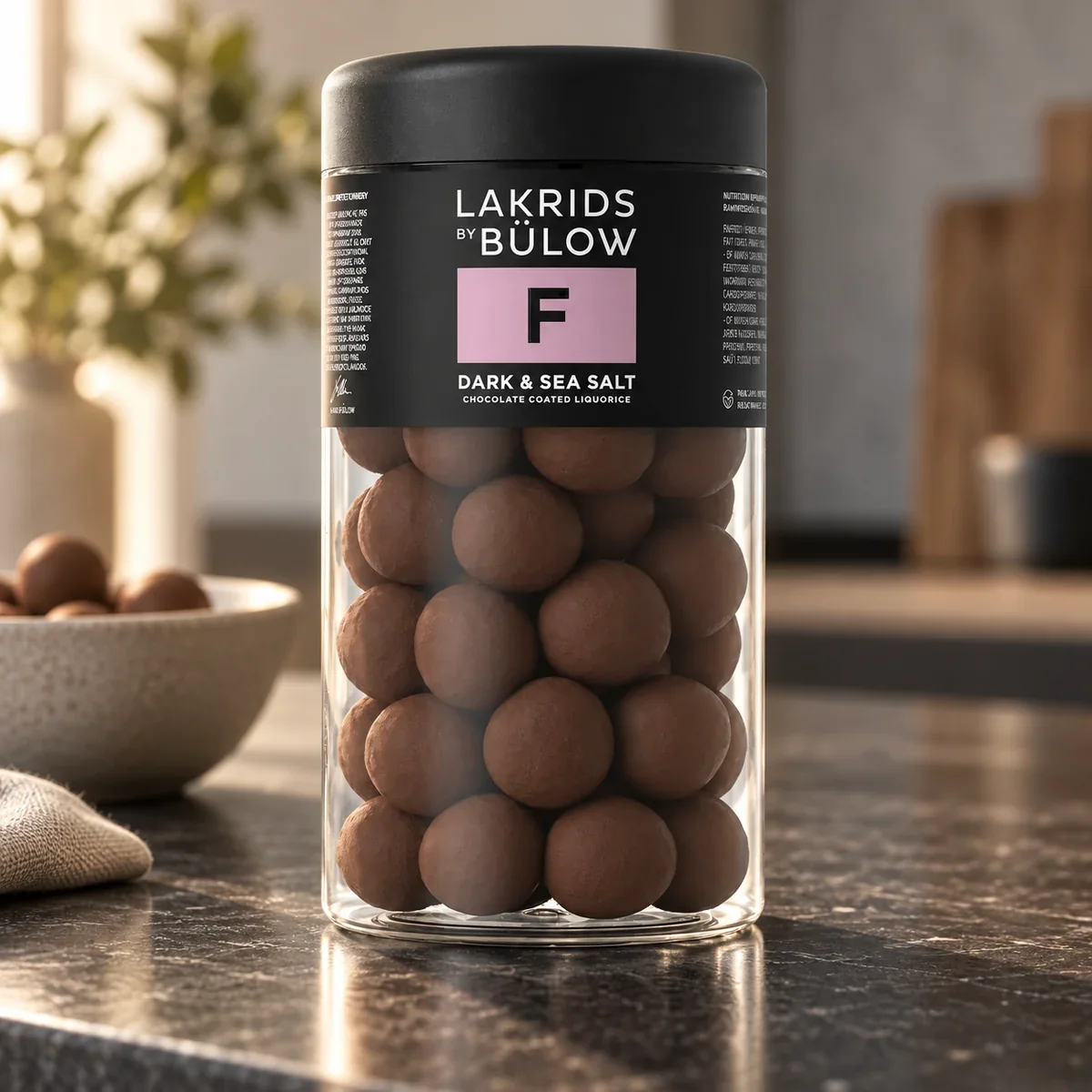 LAKRIDS BY BÜLOW Dark & Sea Salt im schwarzen Glas als hochwertiges Lakritz-Werbegeschenk auf einer modernen Kücheninsel.