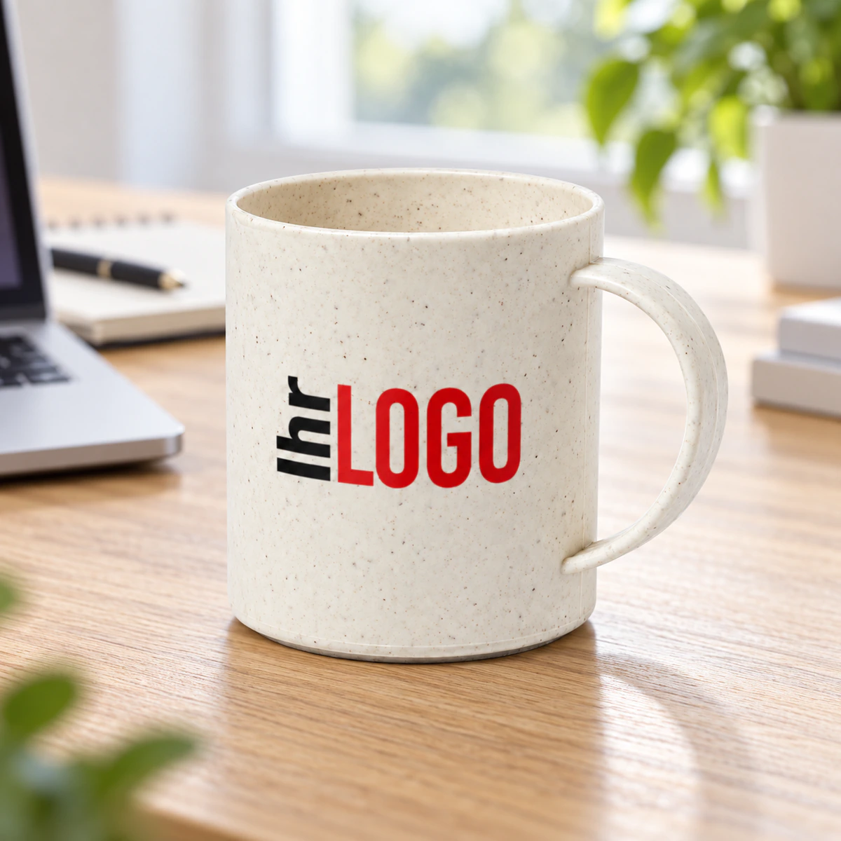 Naturfarbene, gesprenkelte Tasse Esprit mit Logoaufdruck auf einem hellen Schreibtisch neben einem Laptop als Werbeartikel fürs Büro.