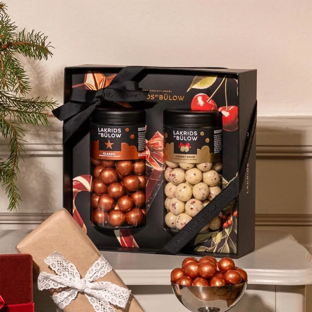 Black Box Classic & Cherry Sour Lakrids by Bülow, 540 g Lakrids by Bülow Black Box mit zwei Regular-Dosen neben Geschenken und Tanne – Firmengeschenk zu Weihnachten