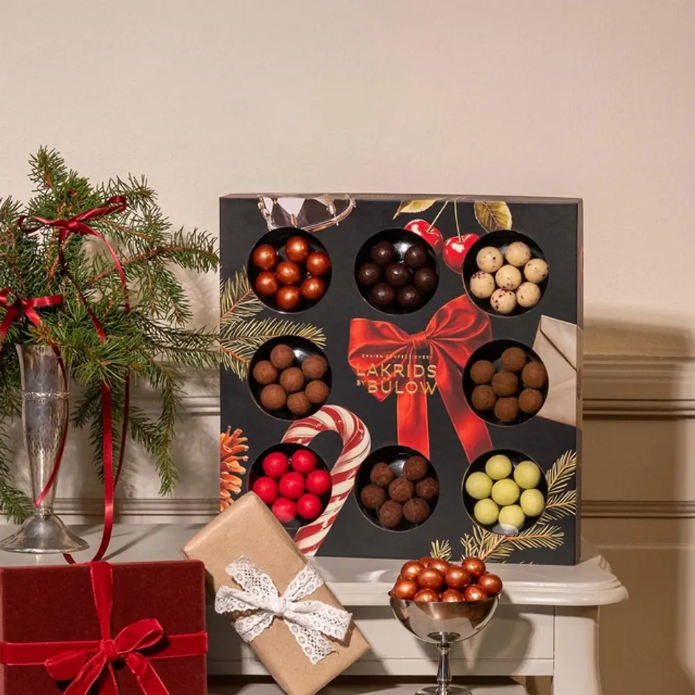Lakrids by Bülow Winter Selection Box mit acht Sorten neben Tannenzweigen – Weihnachtsgeschenk für Kunden