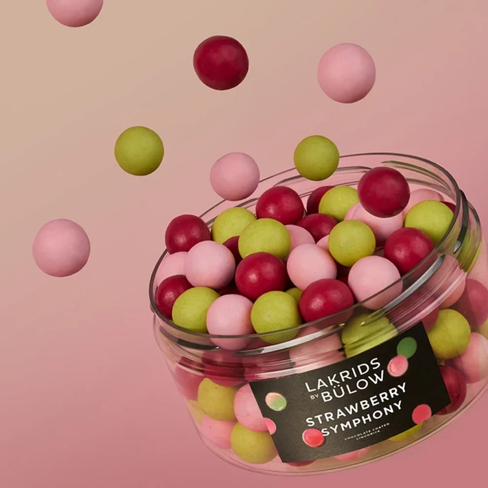 Lakrids by Bülow Strawberry Symphony: offene Dose mit fliegenden Kugeln auf Rosa – Lakritz zum Feiern