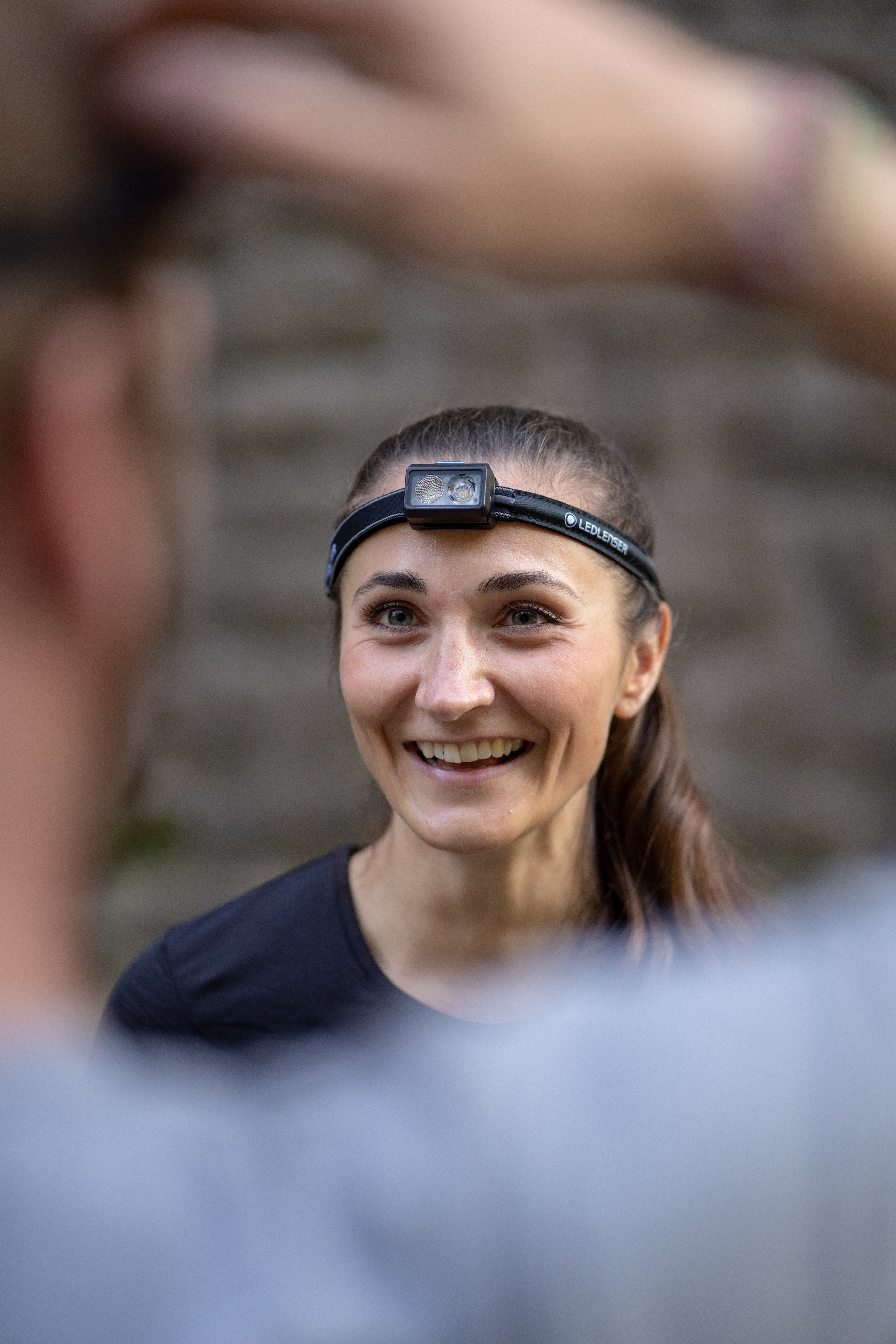 Lächelnde Läuferin mit LEDLENSER NEO3 Stirnlampe im Freien – Laufstirnlampe zum Bedrucken