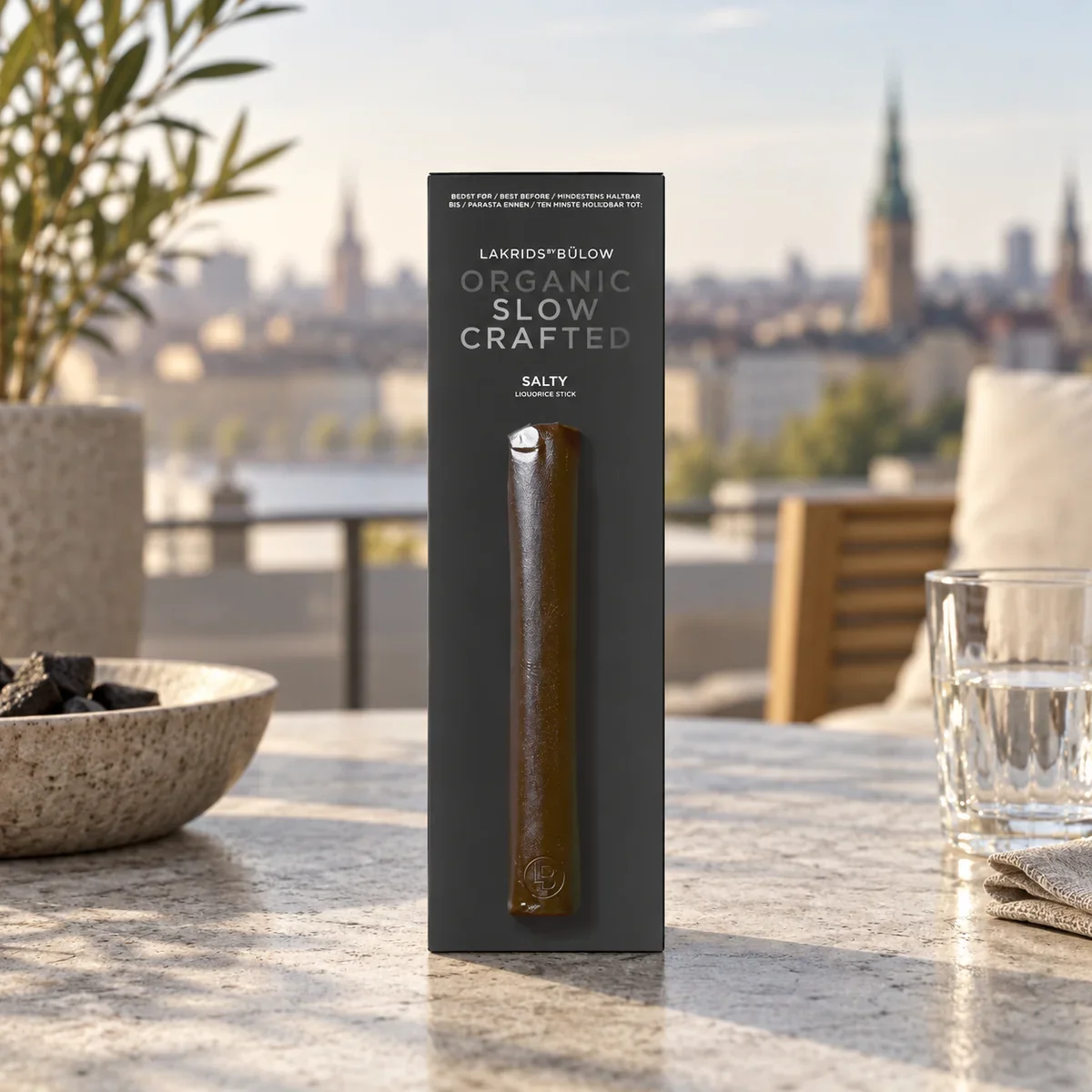 LAKRIDS BY BÜLOW Salty Liquorice Stick als kompaktes Lakritz-Werbegeschenk auf einem Tisch einer stilvollen Außenterrasse.