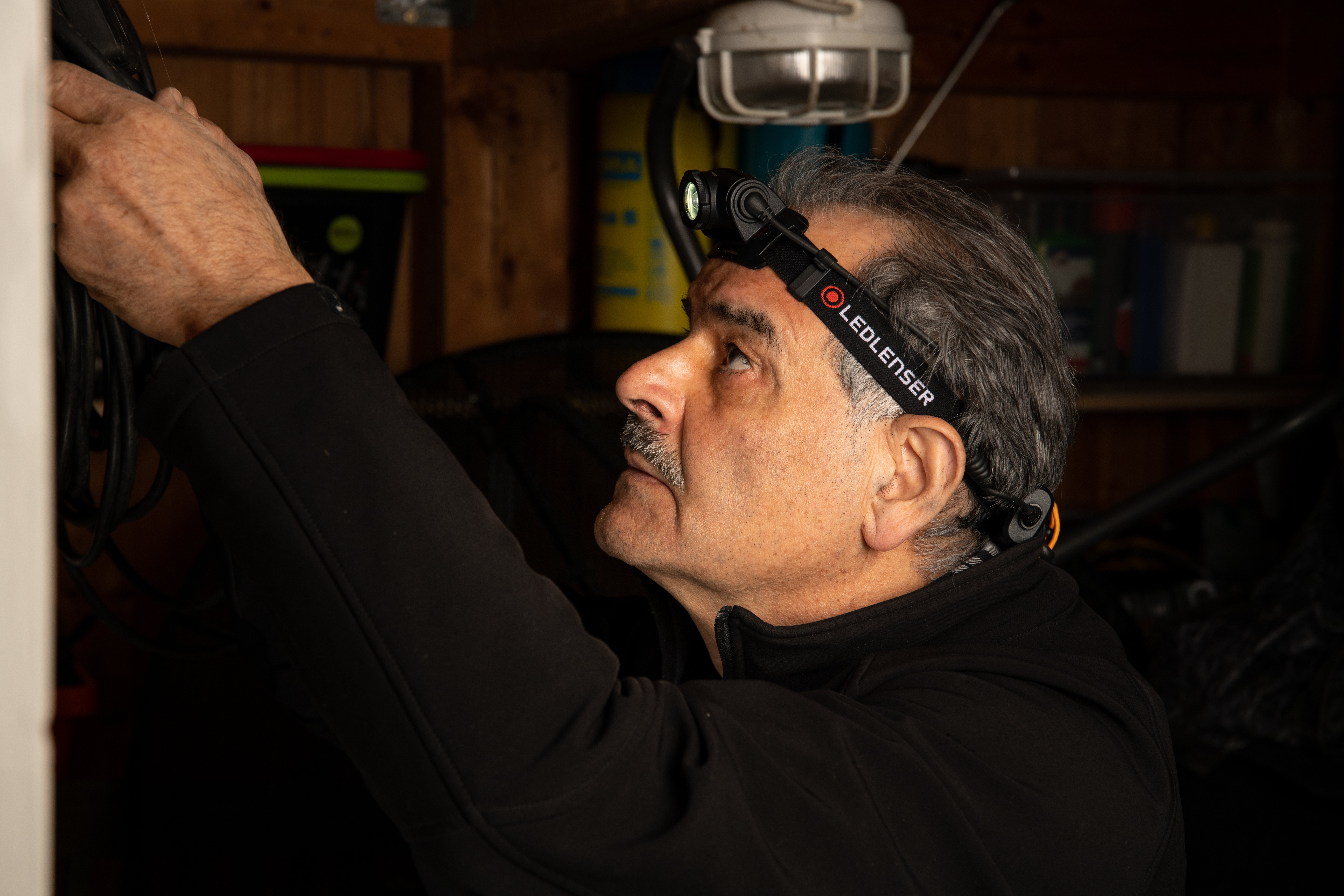 Mann mit LEDLENSER H5 Core Stirnlampe arbeitet in der Werkstatt – Stirnlampe mit Logo für Handwerker