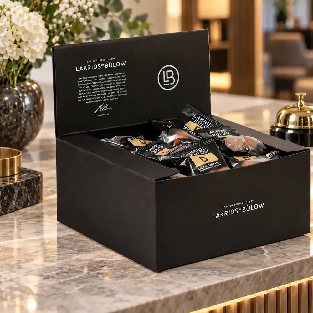 LAKRIDS BY BÜLOW Box of Minis als offene schwarze Lakritz-Geschenkbox auf einem eleganten Empfangstisch im Designhotel.
